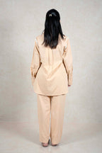 Back view of a woman wearing a Raysham Fashion beige linen-blend long sleeve shirt and trouser co-ord set with lace.