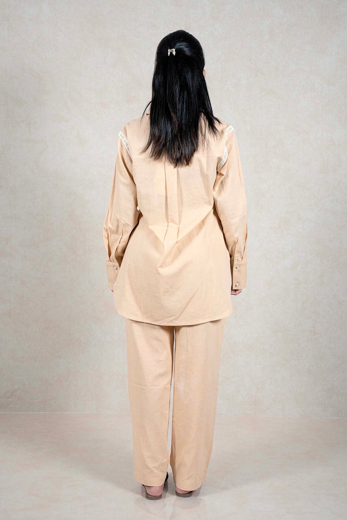 Back view of a woman wearing a Raysham Fashion beige linen-blend long sleeve shirt and trouser co-ord set with lace.