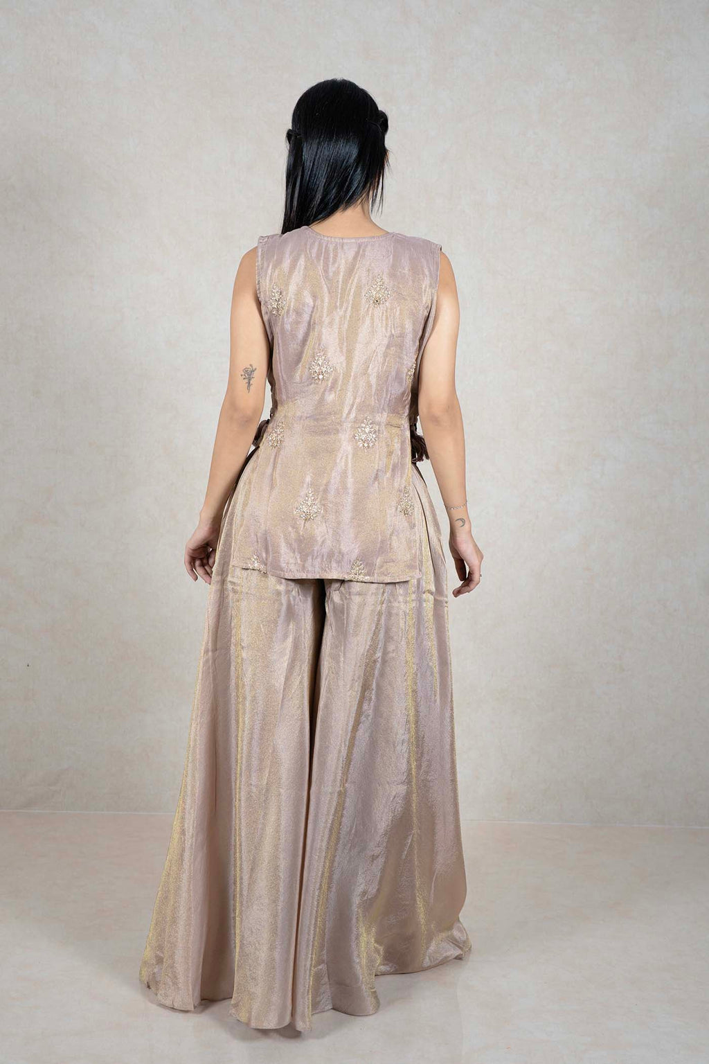 Back view of a woman wearing a champagne Raysham Fashion sleeveless kurta and wide-leg palazzo set with embroidery.