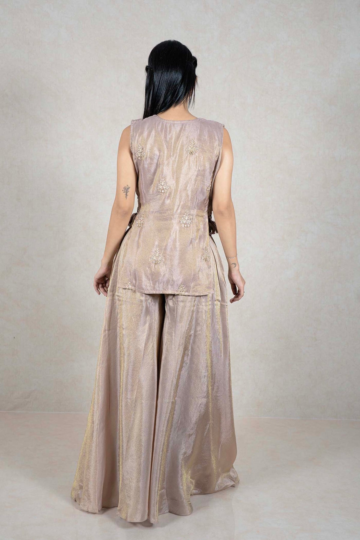 Back view of a woman wearing a champagne Raysham Fashion sleeveless kurta and wide-leg palazzo set with embroidery.