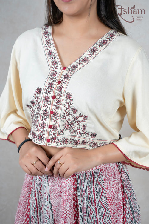 Raysham Fashion off-white crop top with floral embroidery and V-neck, paired with a printed red ethnic skirt.