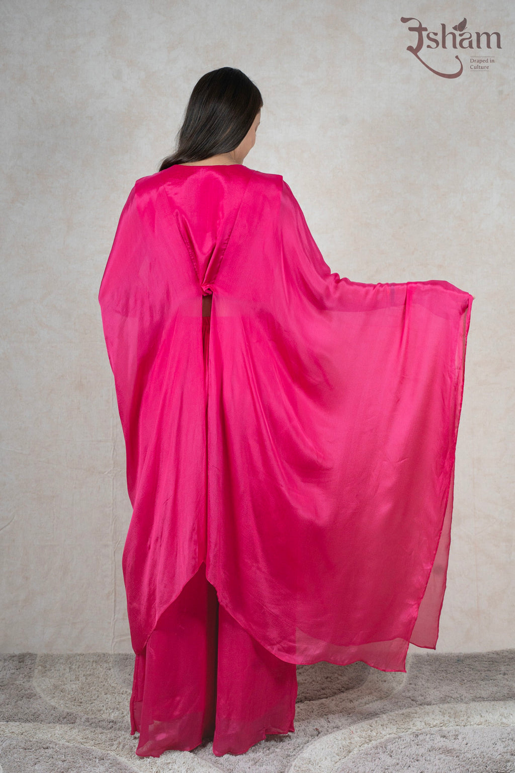 Back view of a woman wearing a Raysham Fashion fuchsia pink sheer kaftan cape with matching wide-leg trousers.