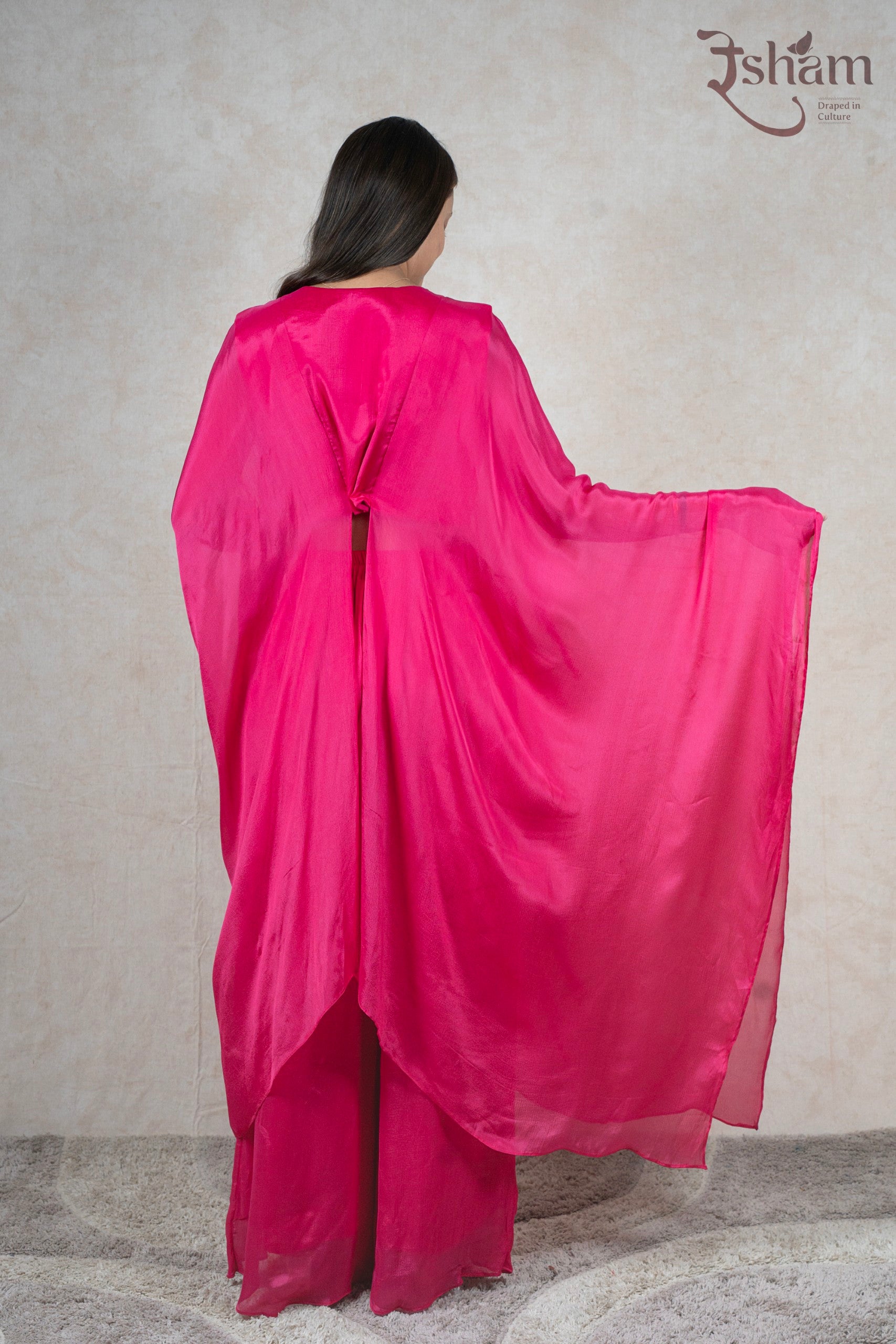 Back view of a woman wearing a Raysham Fashion fuchsia pink sheer kaftan cape with matching wide-leg trousers.