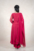 Back view of a woman wearing a Raysham Fashion deep magenta Anarkali suit with a sheer dupatta and gold trim.