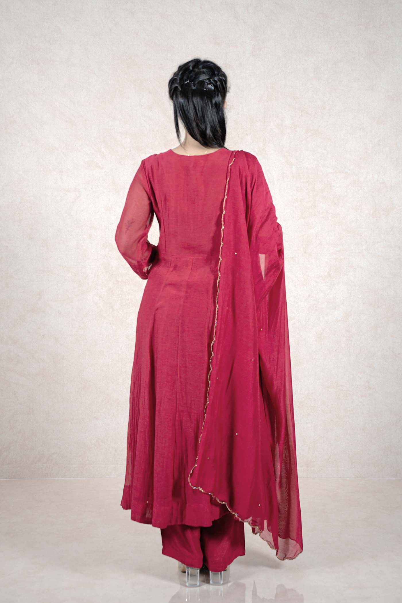 Back view of a woman wearing a Raysham Fashion deep magenta Anarkali suit with a sheer dupatta and gold trim.