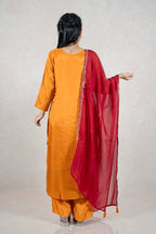 Back view of a woman wearing a Raysham Fashion mustard yellow silk-blend kurta set with a sheer red dupatta.