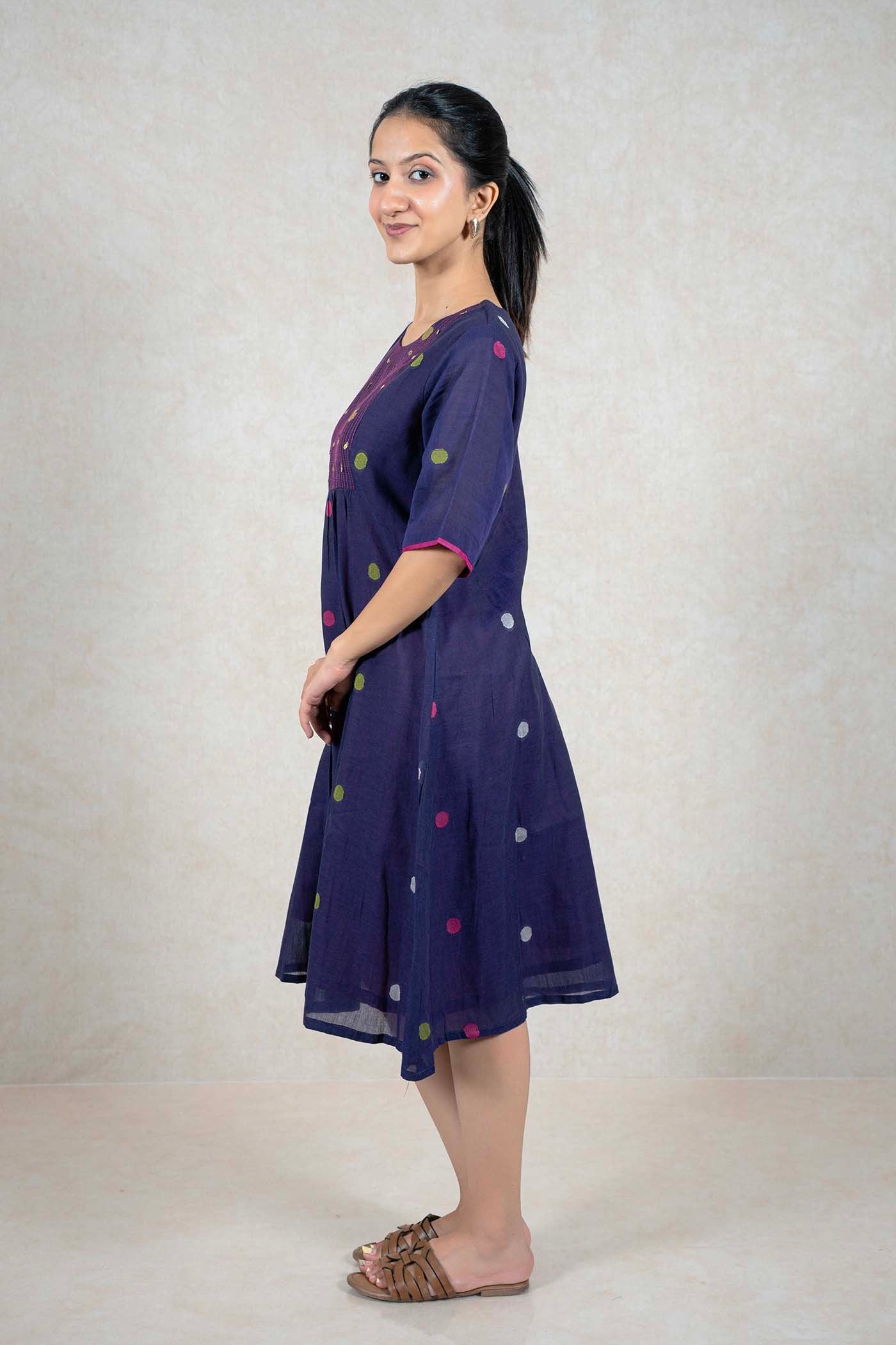 A woman wearing a Raysham Fashion navy blue cotton midi dress with a polka dot pattern, elbow-length sleeves, and pockets