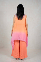 Back view of a woman wearing a Raysham Fashion orange sleeveless layered top and wide-leg trousers with a pink ombre shrug
