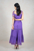 Back view of a woman wearing a Raysham Fashion purple tiered midi dress with lace trim and tie-up shoulder straps.