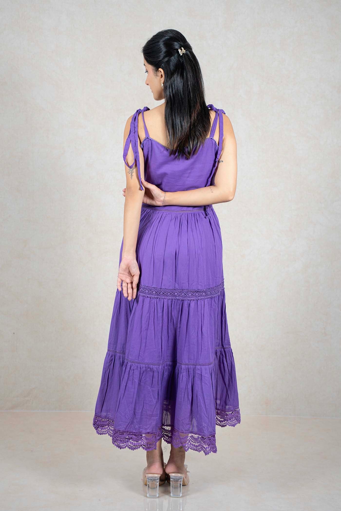Back view of a woman wearing a Raysham Fashion purple tiered midi dress with lace trim and tie-up shoulder straps.