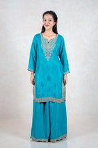 Model wearing a teal Raysham Fashion silk kurta set with intricate multi-colored embroidery and wide-leg trousers.