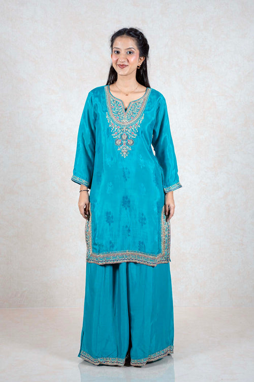 Model wearing a teal Raysham Fashion silk kurta set with intricate multi-colored embroidery and wide-leg trousers.