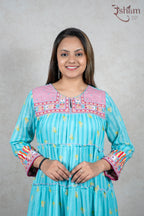 Raysham Fashion turquoise tiered maxi dress with floral print, pink embroidered yoke, and striped cuffs on a model.