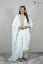 A woman wearing a white Raysham Fashion cotton kurta set with multi-coloured embroidery and a matching dupatta.